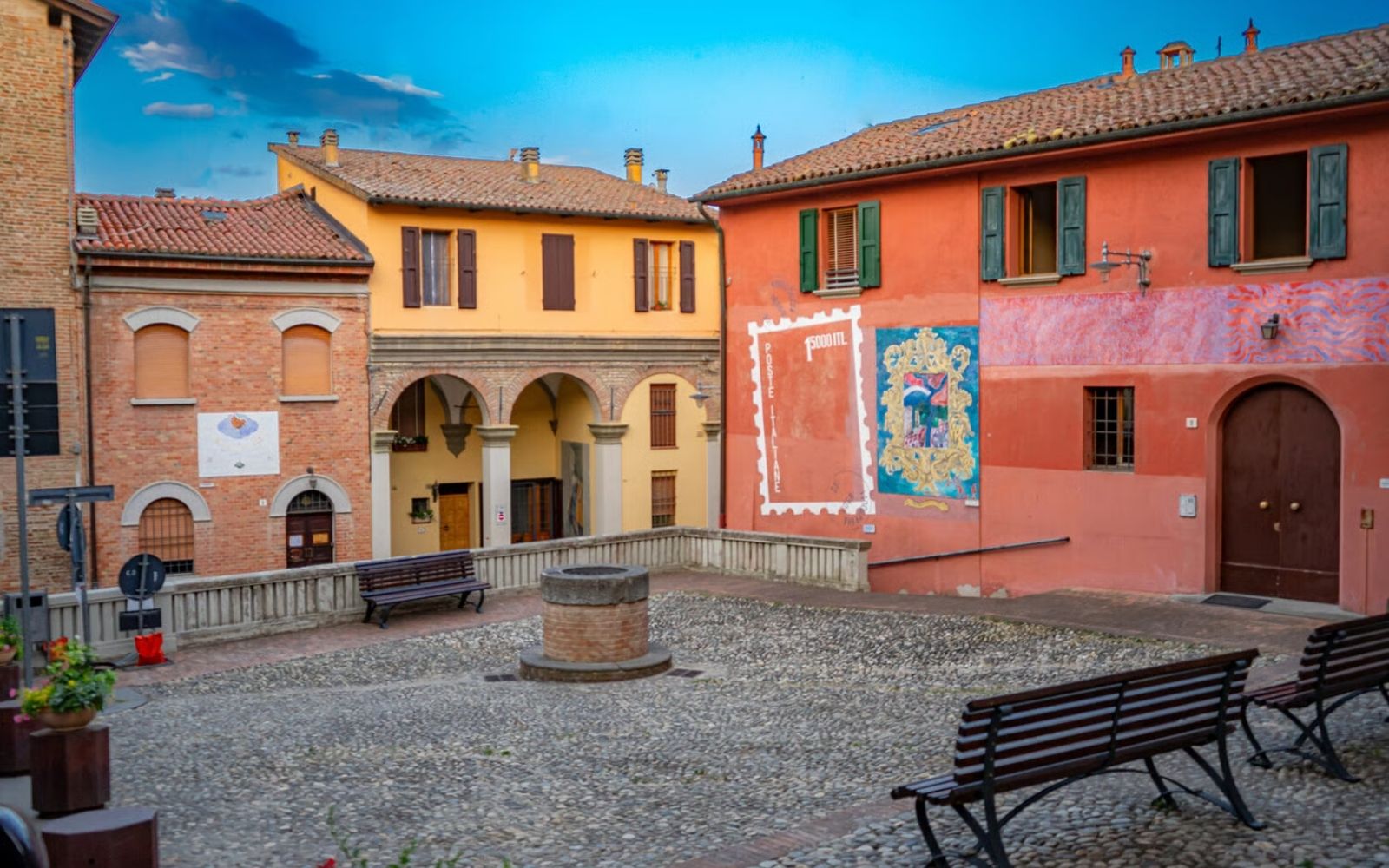 Praça medieval de Dozza com fachadas coloridas, murais e bancos