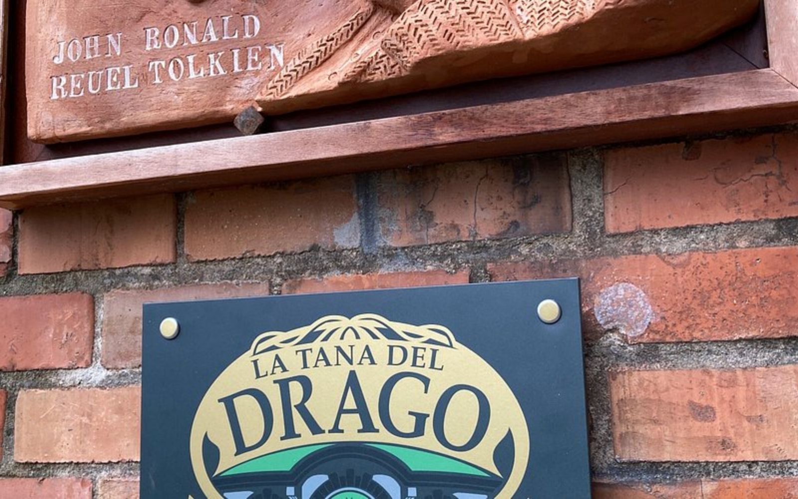 Placa da Tana del Drago em uma parede de tijolos, com referência a J. R. R. Tolkien