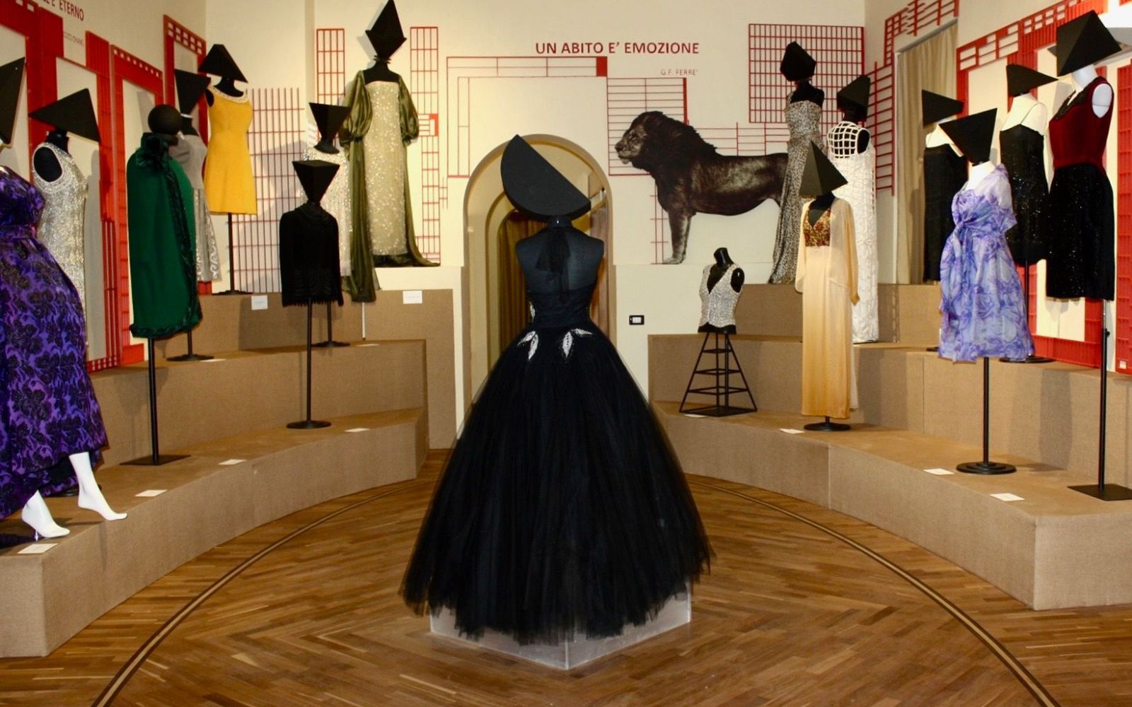 Sala de exposição com vestidos de diferentes estilos e um vestido preto ao centro