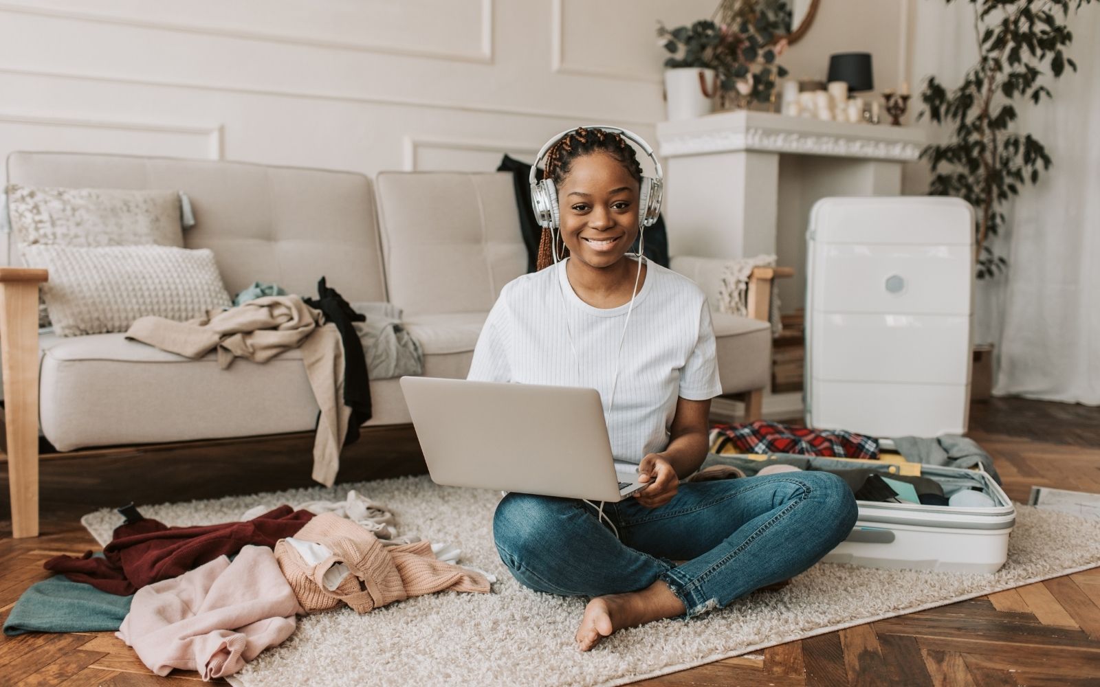 Mulher trabalhando com notebook ao lado de uma mala aberta