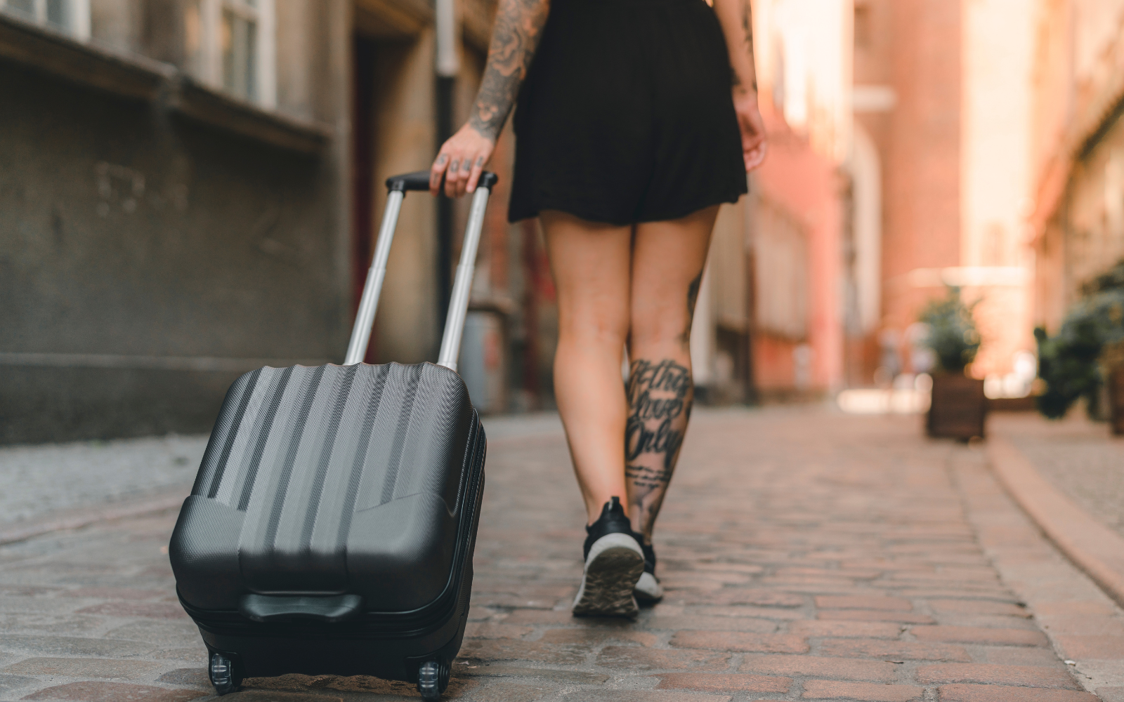 Mulher caminhando com mala por uma rua durante uma viagem sozinha